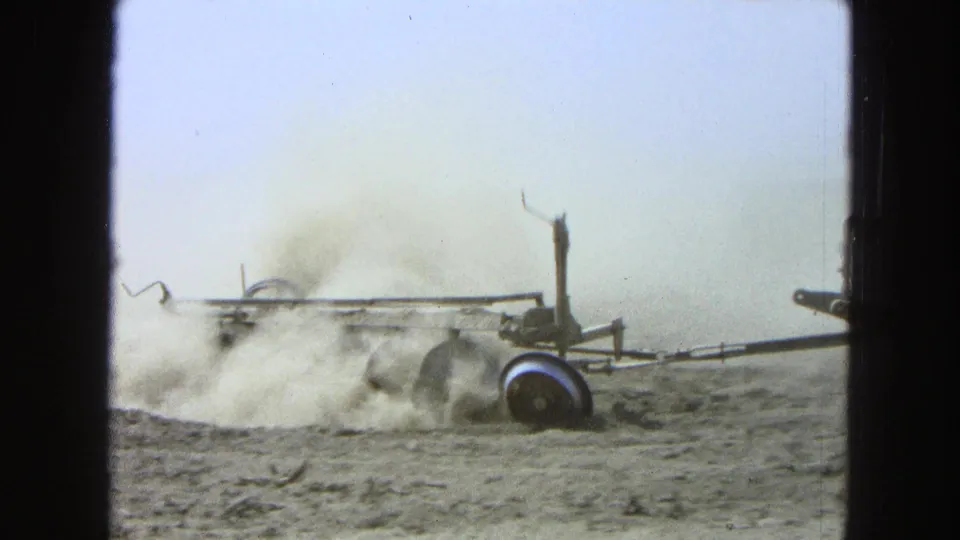 The plowing equipment continues across the dry field in 1965 Pueblo, Mexico footage, with dust drifting behind the metal frame and wheel.
