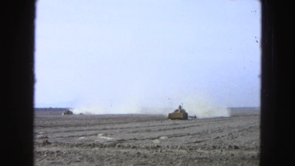 A distant tractor works across a broad dusty field in 1965 Pueblo, Mexico footage, with the driver barely visible and a dust cloud trailing behind.