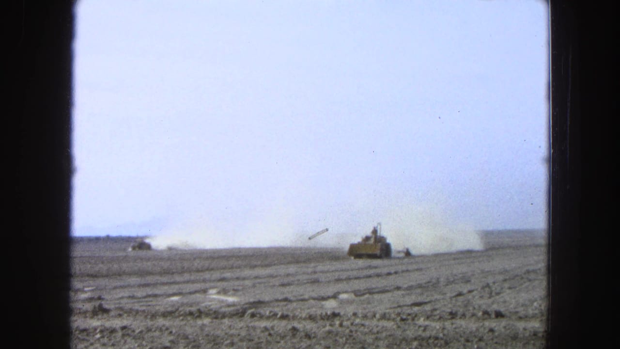 Yellow tractor works across a dusty field under a pale sky, framed by dark film borders.