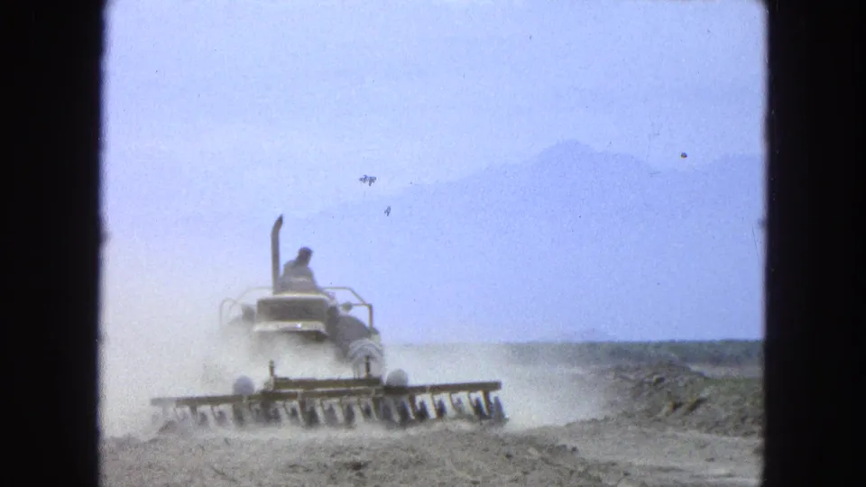 The final frame shows the tractor in the dry rural landscape, its blades near the ground and dust drifting behind.