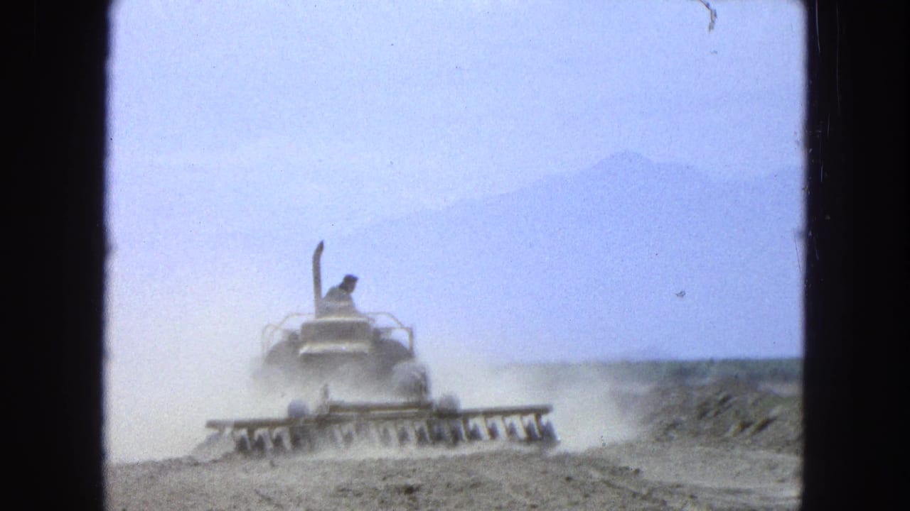 Dust rises around a tractor as an operator works along a dry field track.