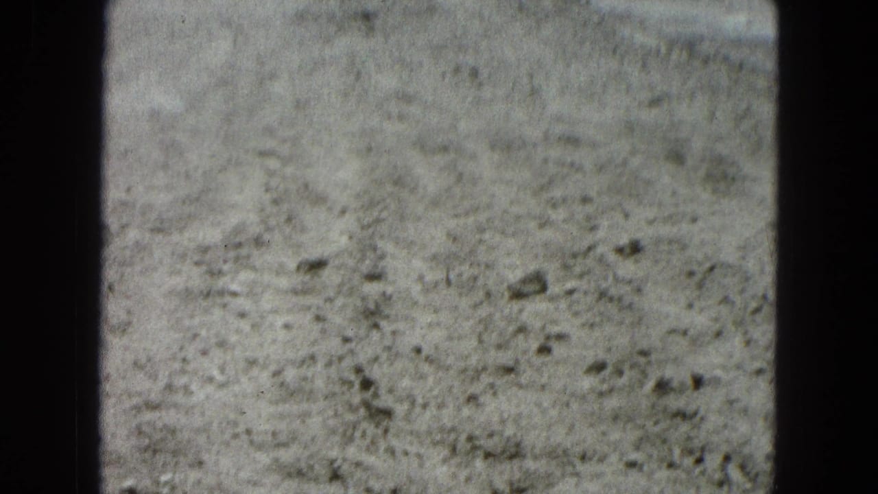 Rocky pale ground seen through an 8mm film frame with dark gate edges.