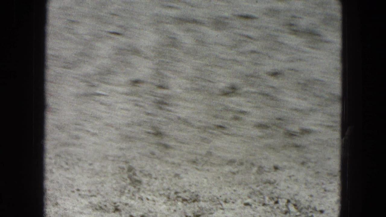 Flat dusty terrain with scattered stones and visible film-frame borders.