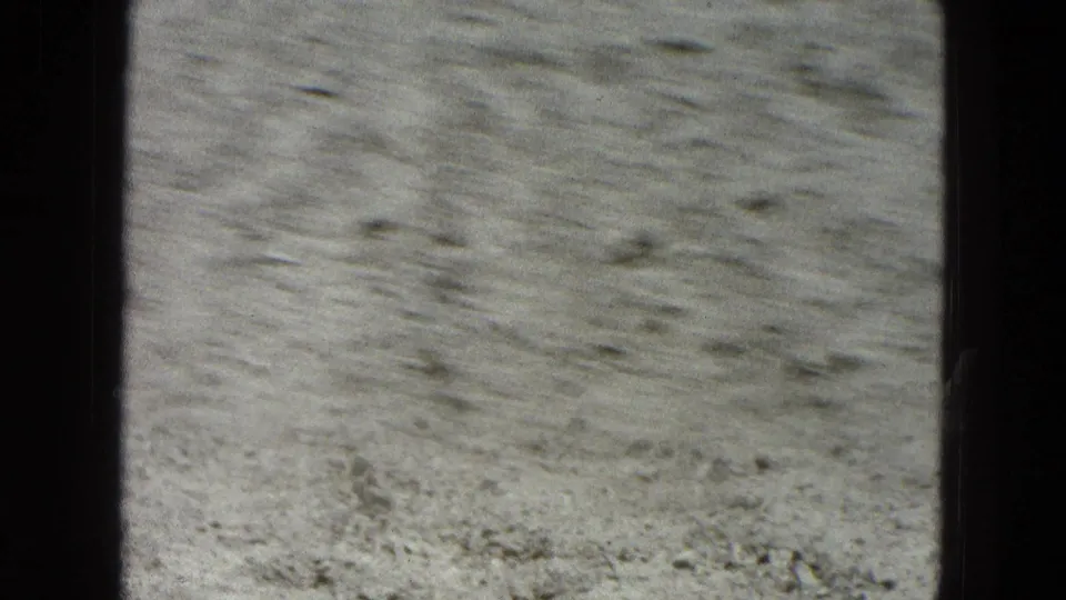 Muted 8mm frame of dusty arid ground in Pueblo, Mexico, with scattered stones and soft grain.