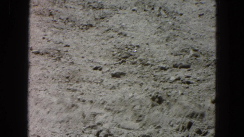 Final 8mm frame showing rocky, barren ground with faint track-like marks in the arid Pueblo, Mexico setting.