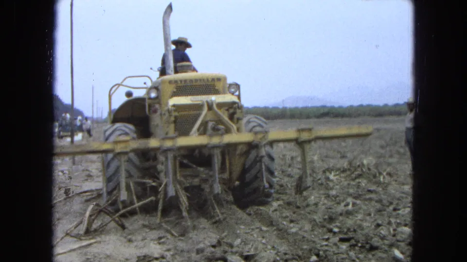 1965 Pueblo Mexico 8mm view of the tractor and soil-working attachment from a close rear angle.