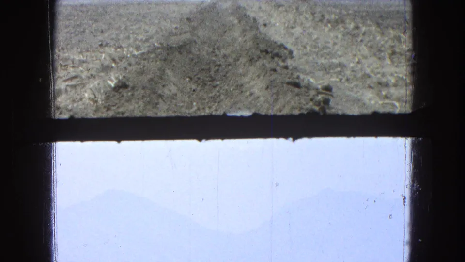 Pueblo, Mexico 1965 travel footage shows a pale sky and dry dirt track beyond window mullions.