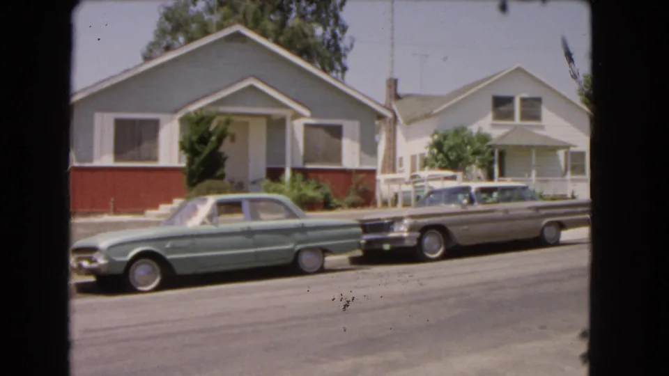 End frame of a 1966 Barstow home-movie shot with parked cars and quiet residential houses.