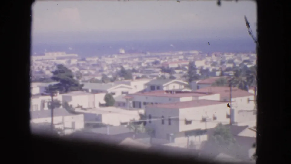 Elevated 1966 Barstow view over low buildings, rooftops, trees, and a hazy horizon.