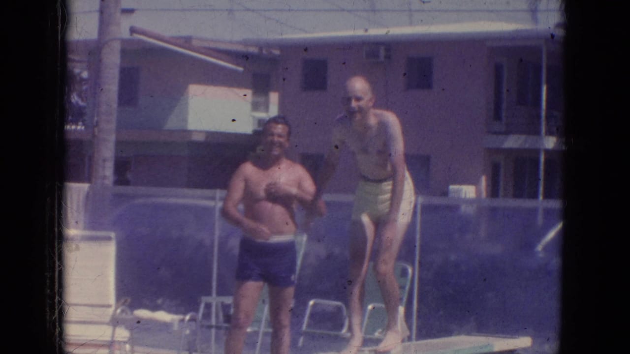 1966 Florida resort pool frame showing two adult men near a diving board, one standing on the board.