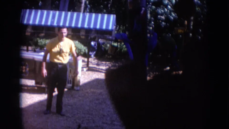 Near the end of the 1966 Busche Gardens shot, the man remains by the parrots as dark foreground shadow covers part of the frame.