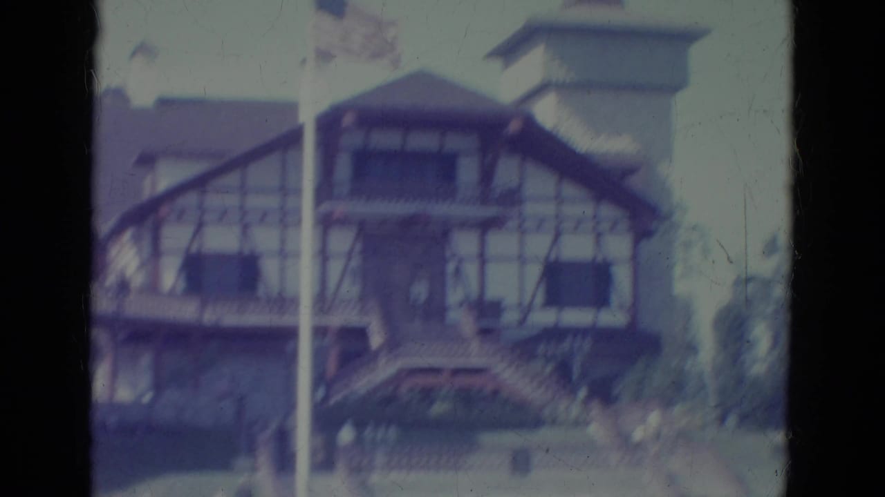 1966 Florida 8mm frame showing a Tudor-style attraction building, tower, steps, and flagpole from a visitor viewpoint.