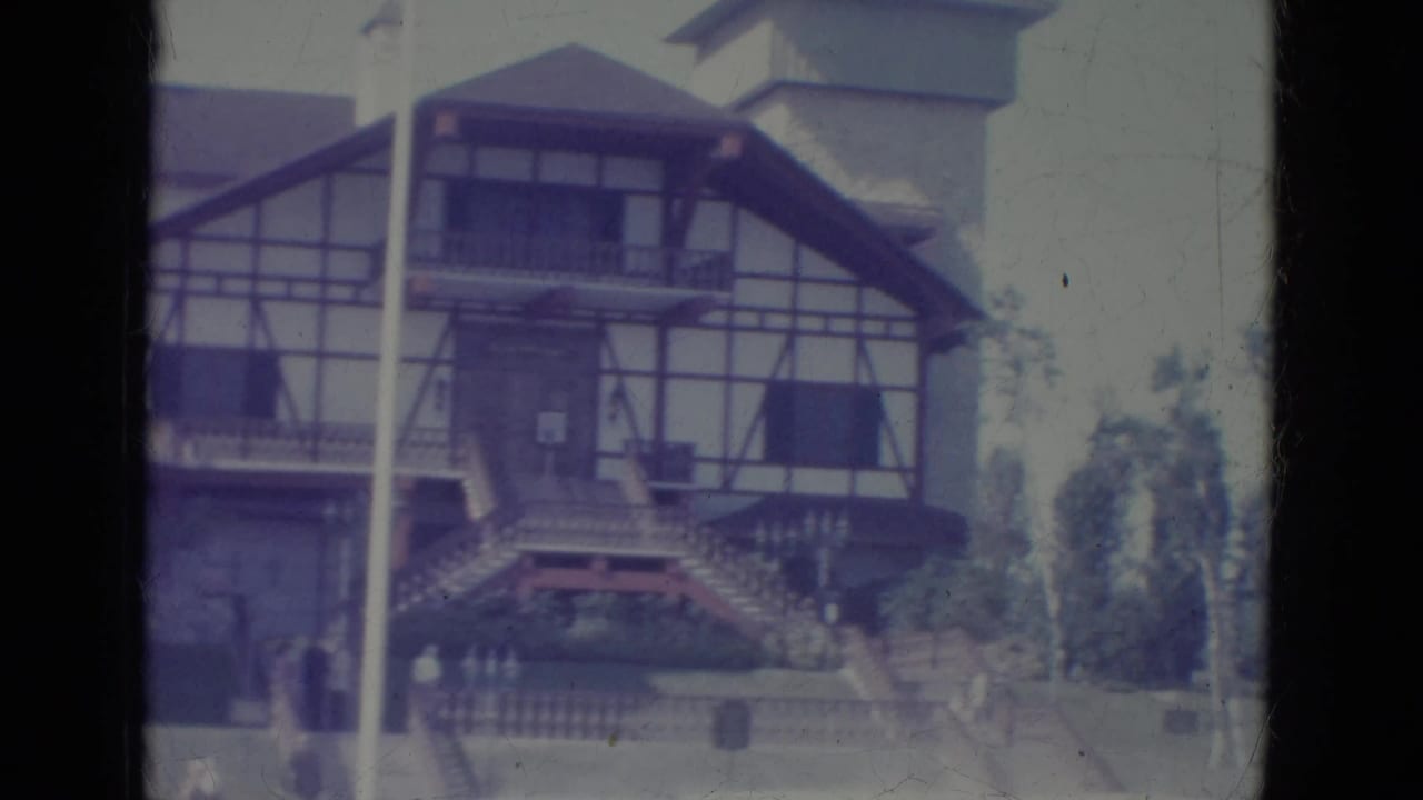 Tudor-style building and flagpole framed from the front in faded 8mm color.