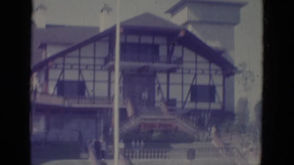 Faded 8mm frame from the 1966 Florida clip showing the Tudor-style building, flagpole, balcony, and front steps.