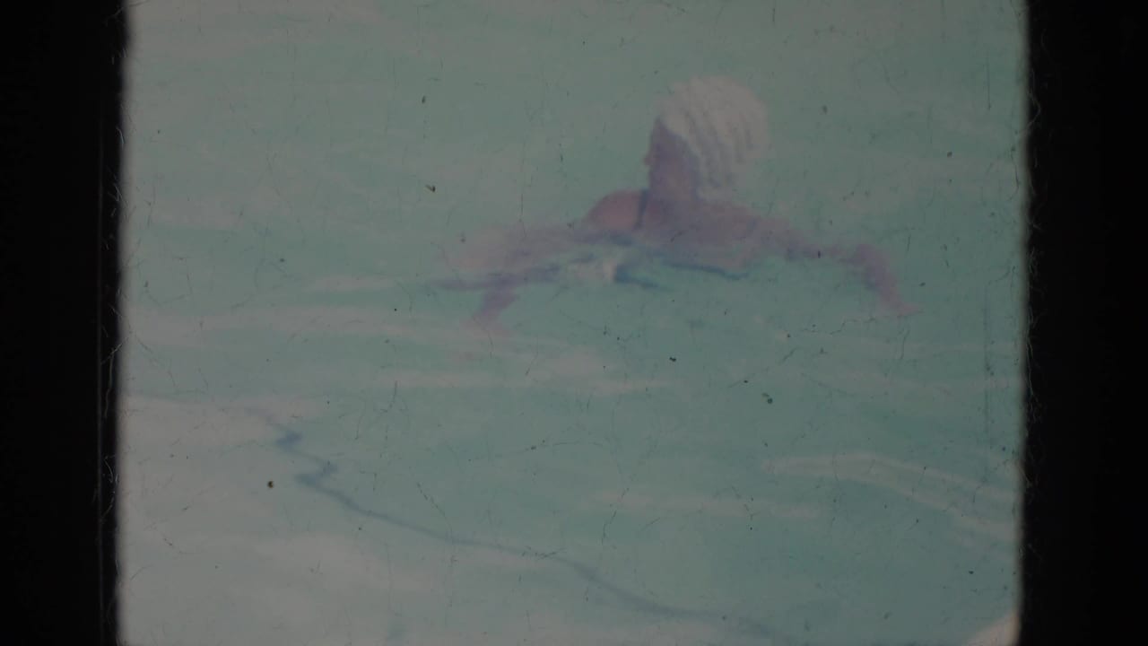 1966 Super 8 frame from Busche Gardens, Florida, showing a woman in a white swim cap moving through a pool.