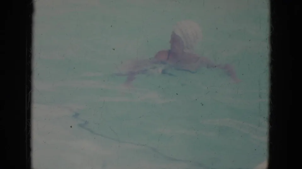 1966 Super 8 frame from Busche Gardens, Florida, showing a woman in a white swim cap moving through a pool.