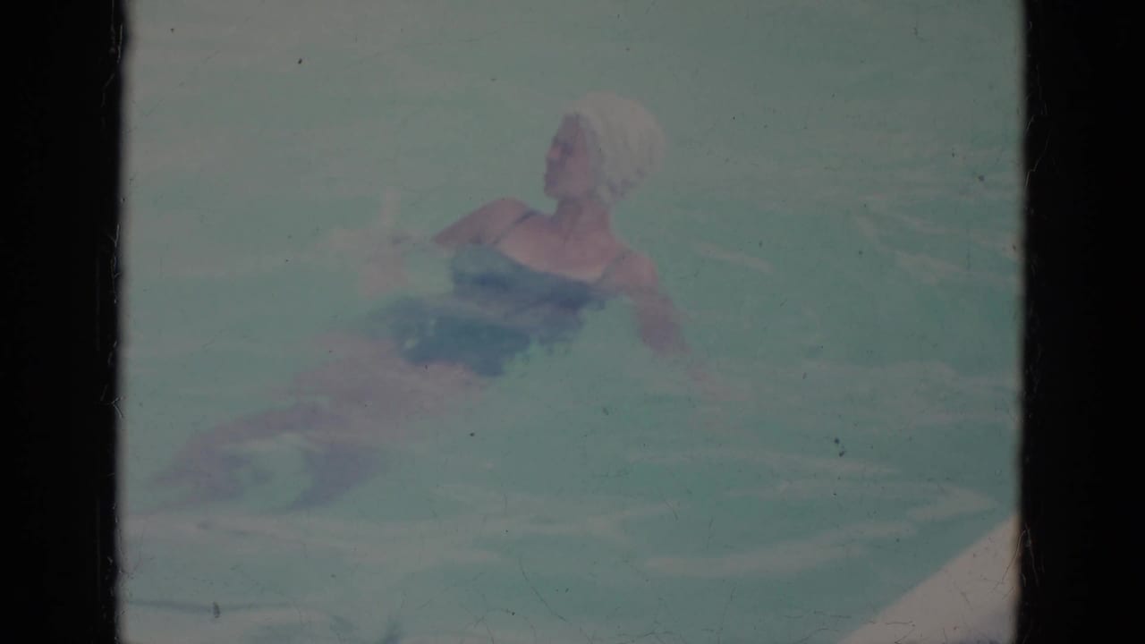 Woman in swim cap floating on her back in a pool.