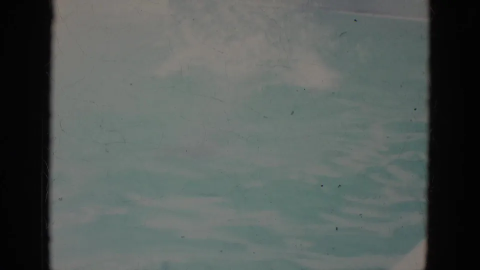 End frame of the 1966 Super 8 pool clip with rippling water and the swimmer partly visible near the top of frame.