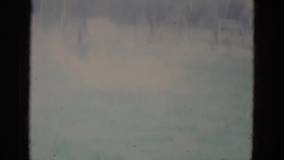 A faded 8mm frame shows the pool area mostly obscured by bright splash, exposure bloom, and soft color from the dive.