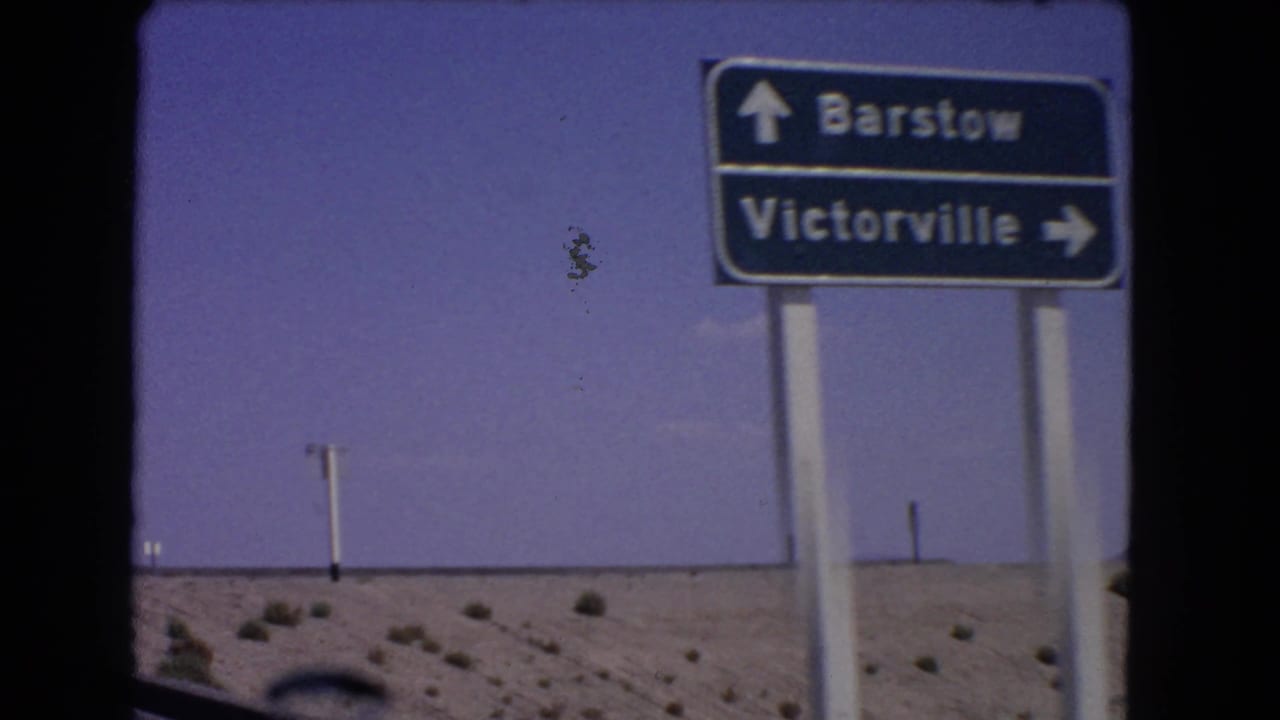 The vehicle passes closer to the Barstow and Victorville directional sign.