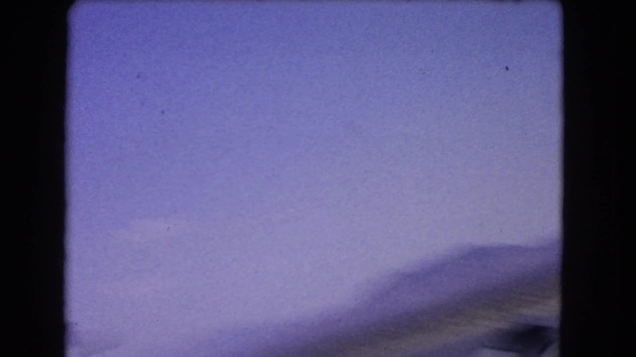 Opening 1966 8mm frame appears blurred, with pale sky, distant mountains, and dark film-gate borders.