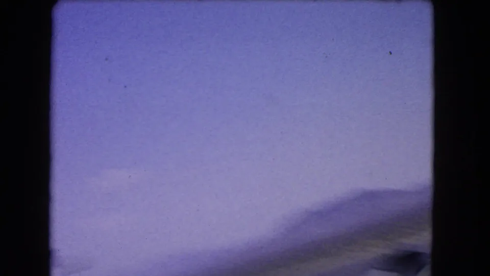 Opening 1966 8mm frame appears blurred, with pale sky, distant mountains, and dark film-gate borders.