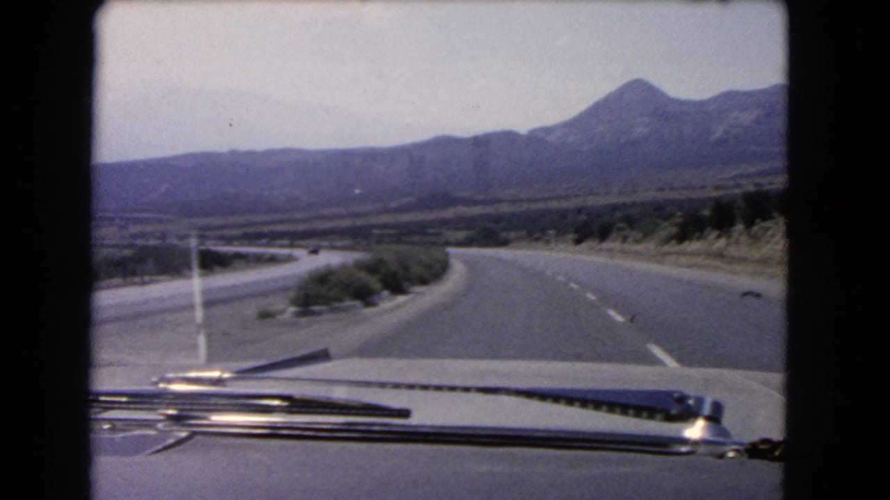 1966 California 8mm windshield view showing a two-lane highway curving through dry terrain toward a mountain range.