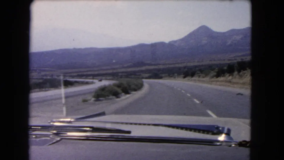 1966 California 8mm windshield view showing a two-lane highway curving through dry terrain toward a mountain range.