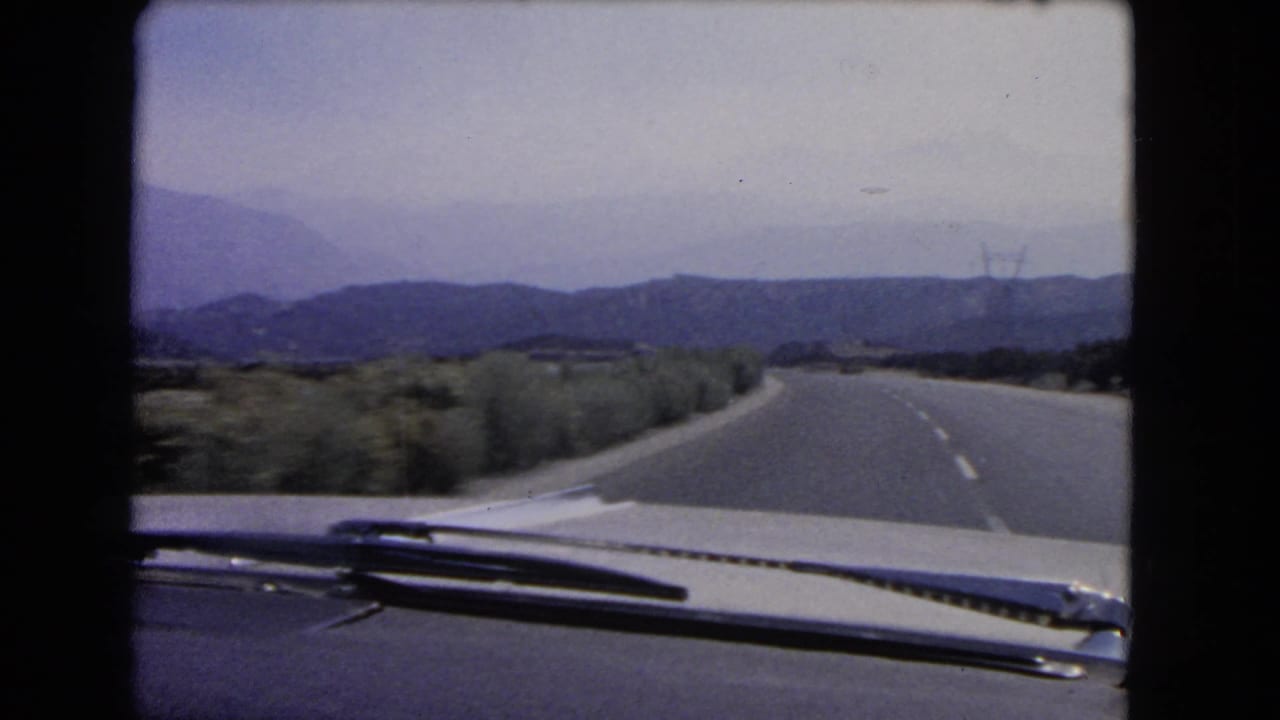 The final frame shows a windshield POV on a quiet California highway, with roadside brush, distant hills, and utility towers visible.