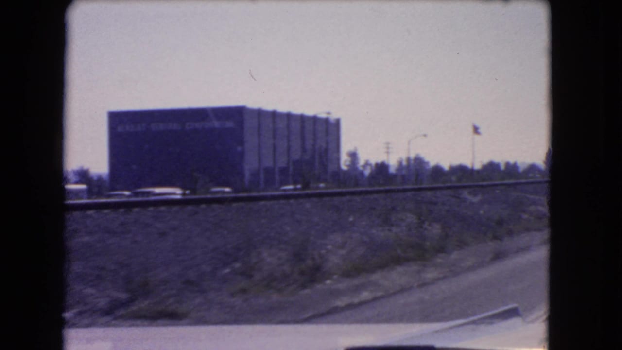 Roadside building and freeway embankment viewed from a moving vehicle.