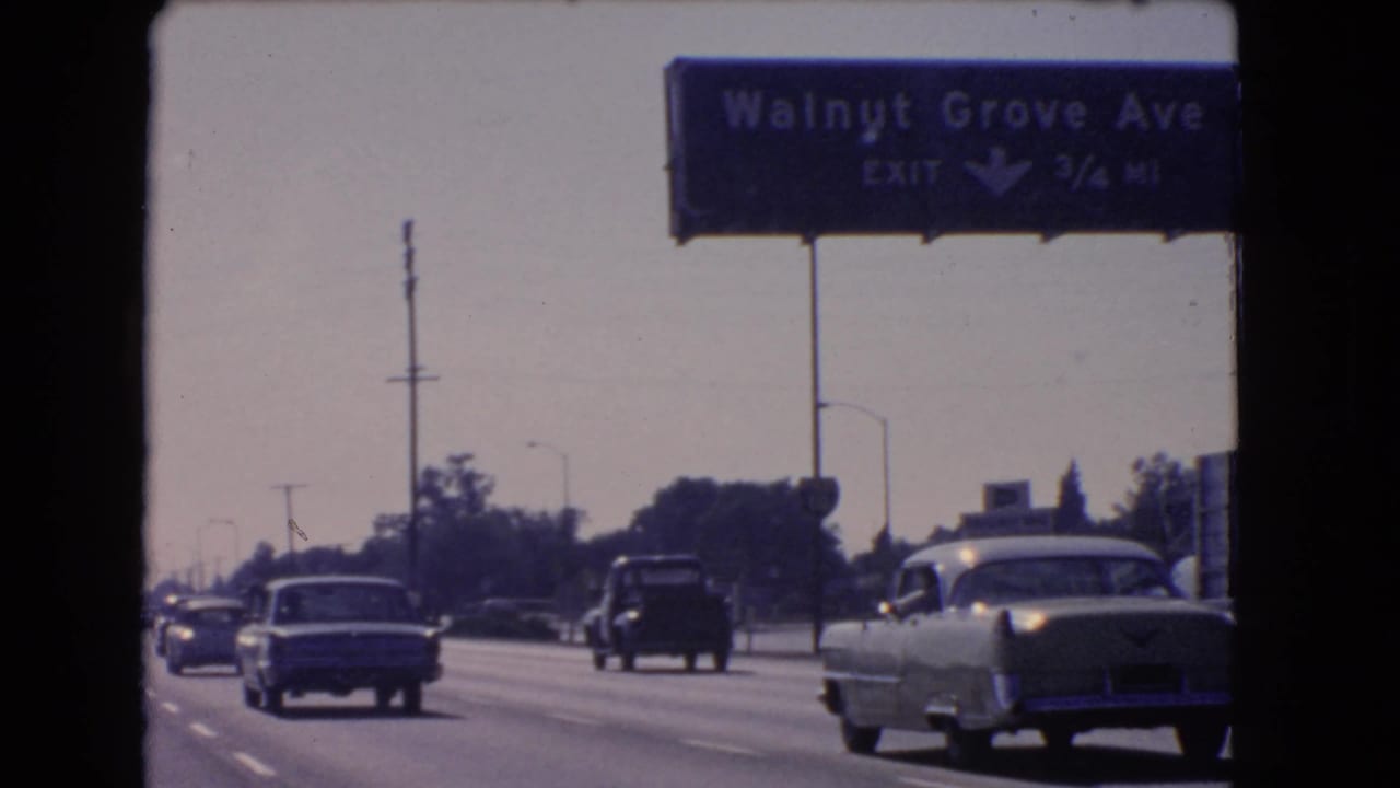 1966 California road scene with a Walnut Grove Ave exit sign above vintage traffic on a multi-lane highway.