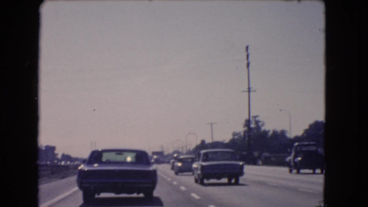 1966 California highway view with sedans and a pickup truck traveling in steady daytime traffic.