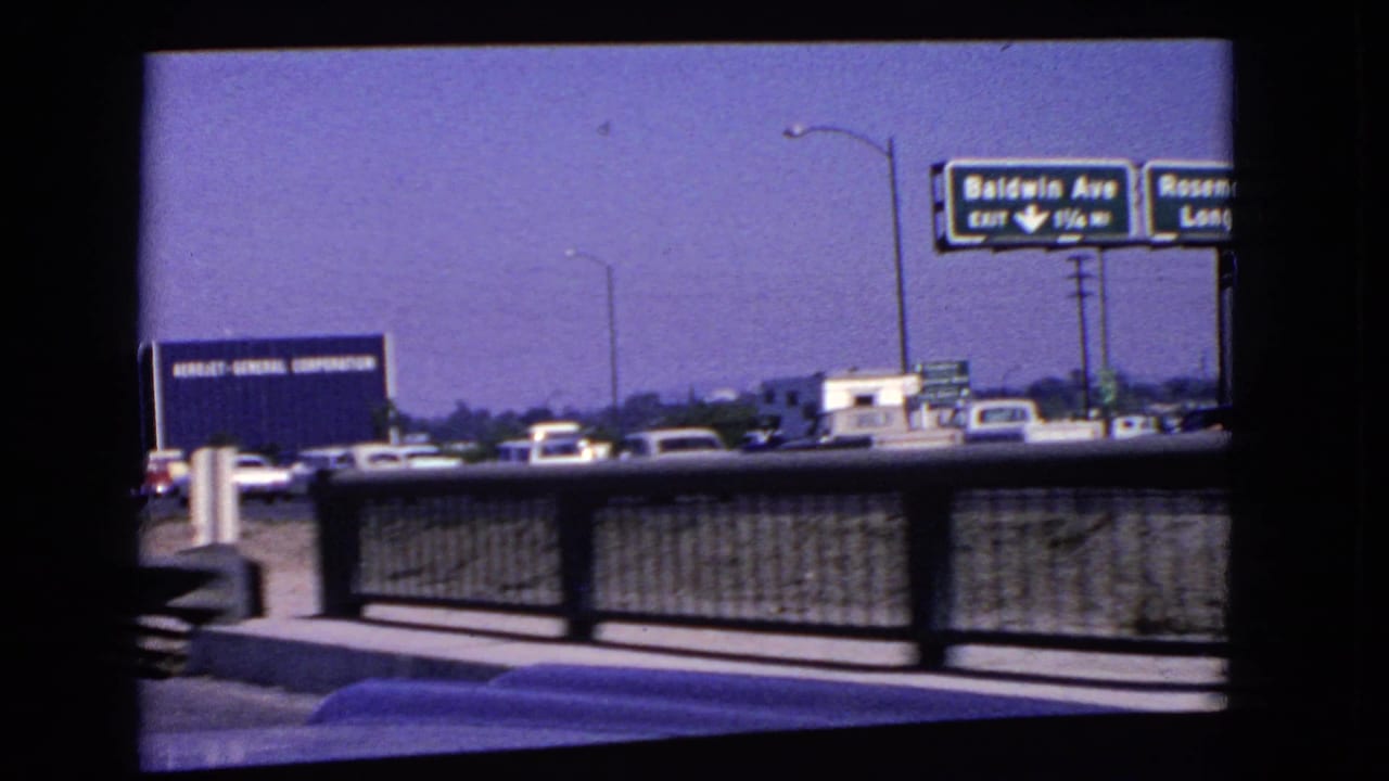 1966 California highway frame showing bridge railing, traffic, exit signage, and an Aerojet-General Corporation billboard.