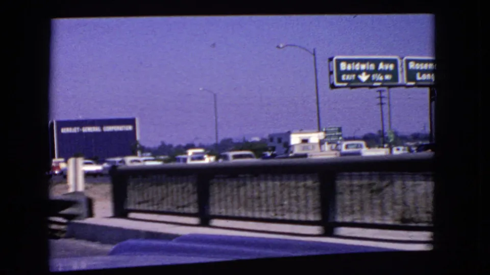 1966 California highway frame showing bridge railing, traffic, exit signage, and an Aerojet-General Corporation billboard.