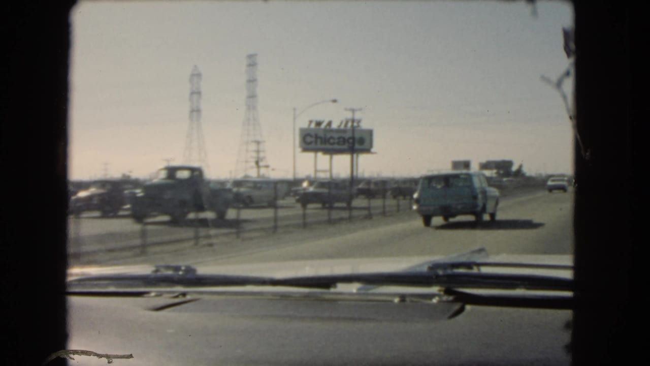 1966 California road-trip footage from a car interior, with vehicles ahead, roadside power towers, and a TWA Jets Chicago billboard.