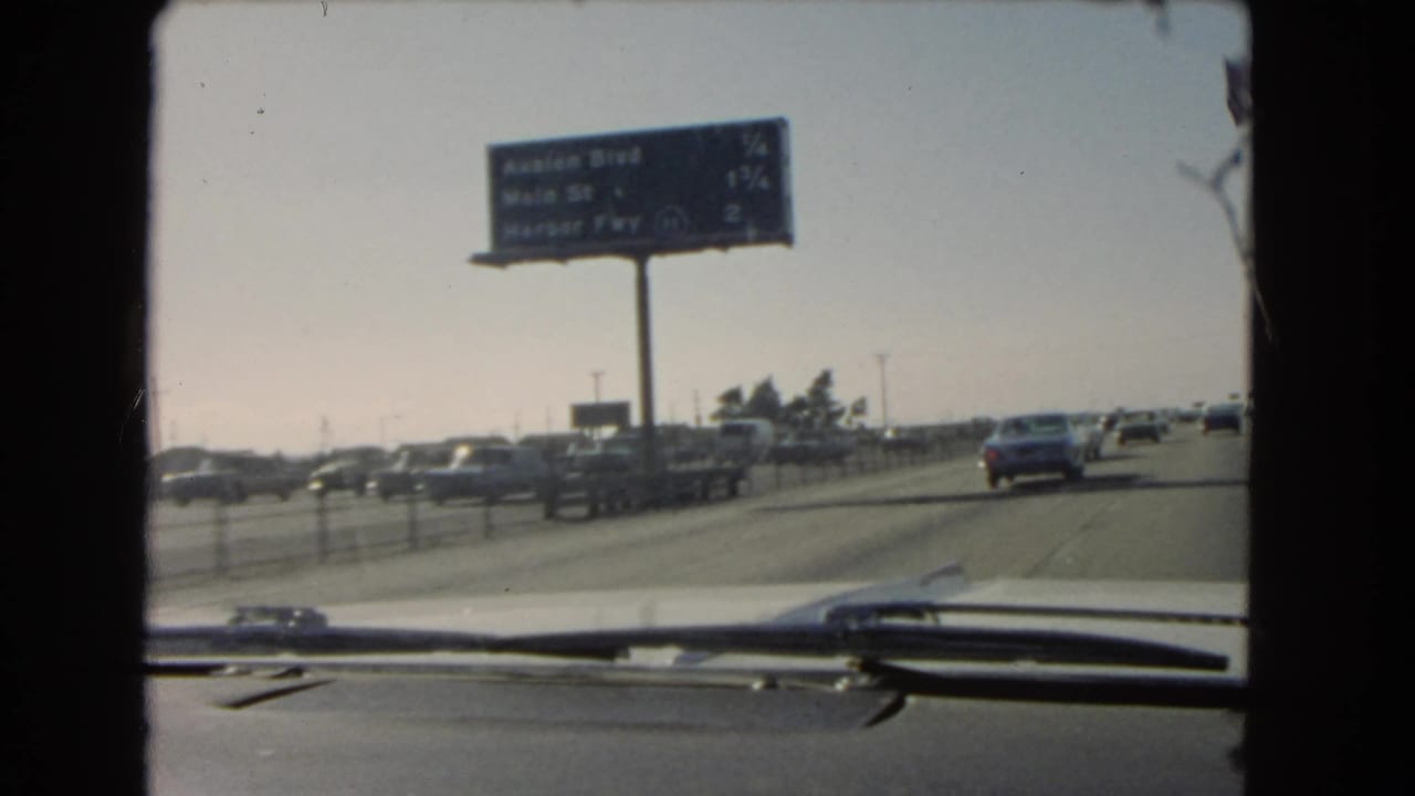 1966 California highway view showing an overhead sign for Avalon Blvd, Main St, and Harbor Fwy, with traffic seen from inside a car.