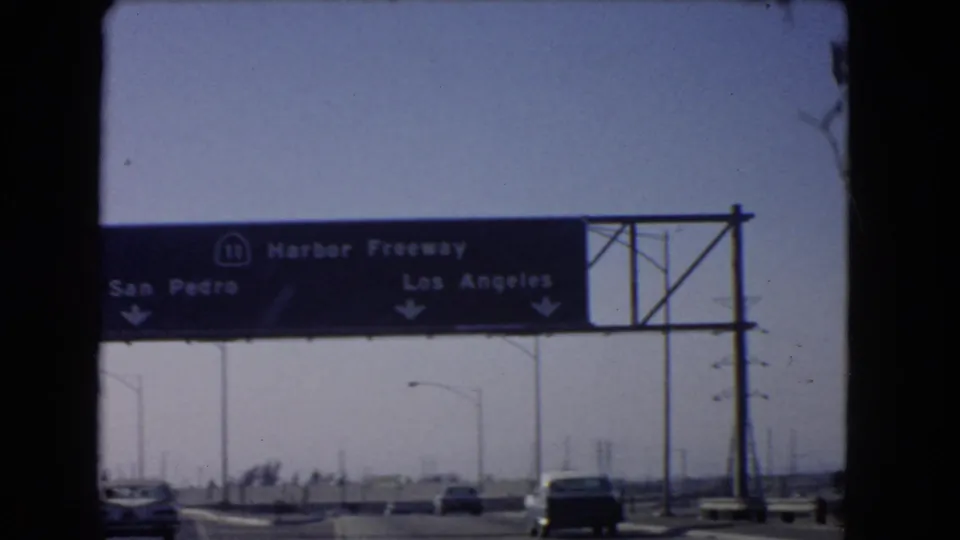 1966 California 8mm frame showing a Harbor Freeway overhead sign for San Pedro and Los Angeles above cars on the road.