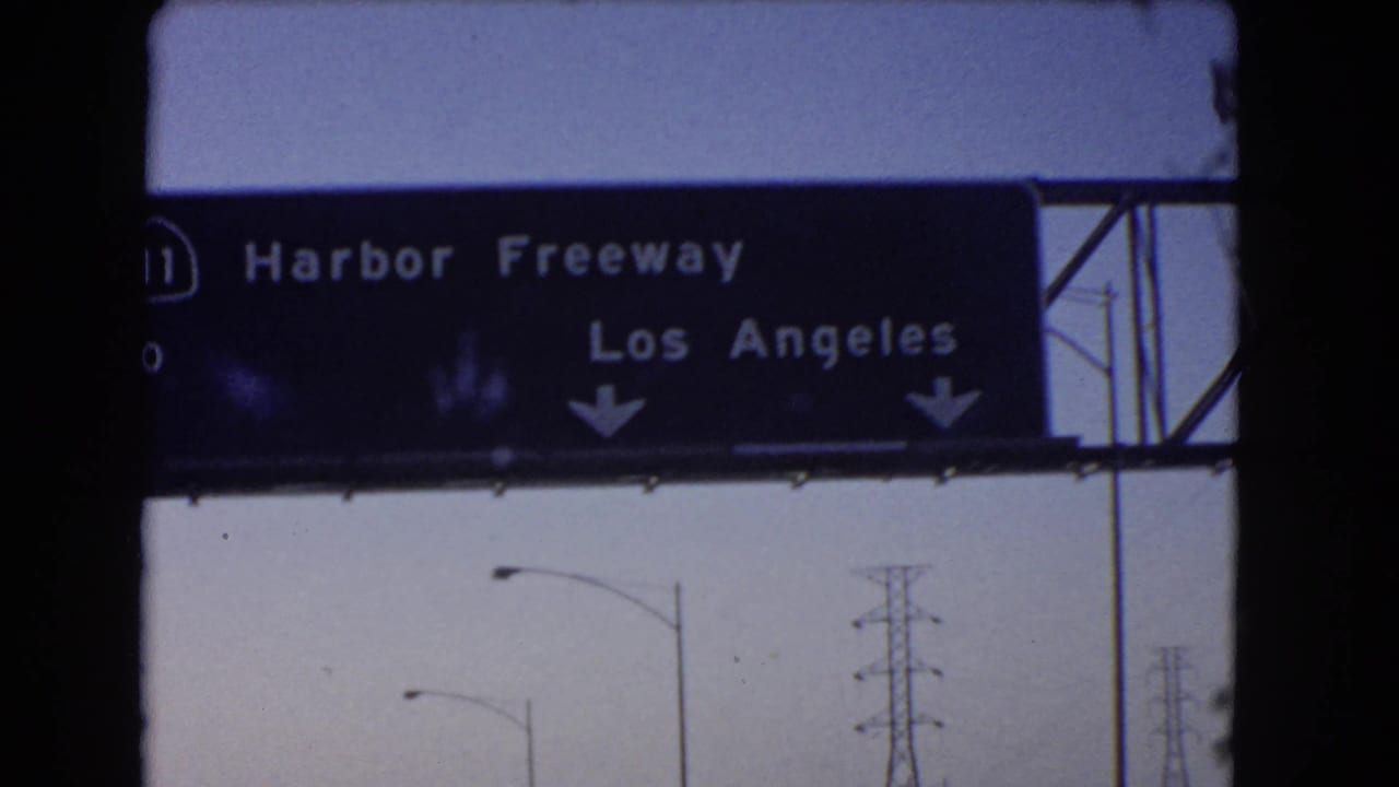 1966 California 8mm frame with a closer passenger-view angle on the Harbor Freeway sign for Los Angeles.