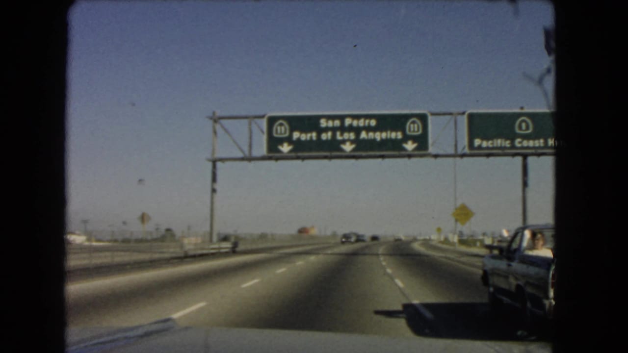 1966 California road footage shows overhead green signs for San Pedro and the Port of Los Angeles on Route 11 above a multi-lane highway.