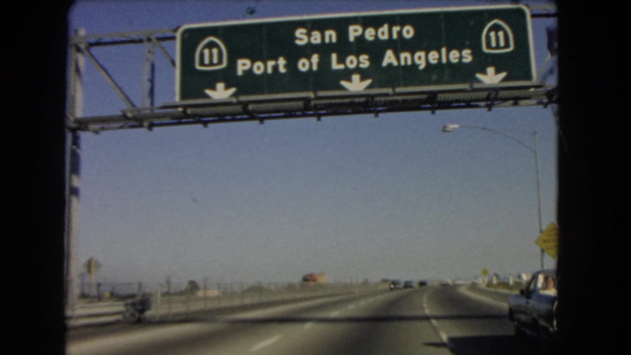 Freeway view under a green sign for San Pedro and Port of Los Angeles.