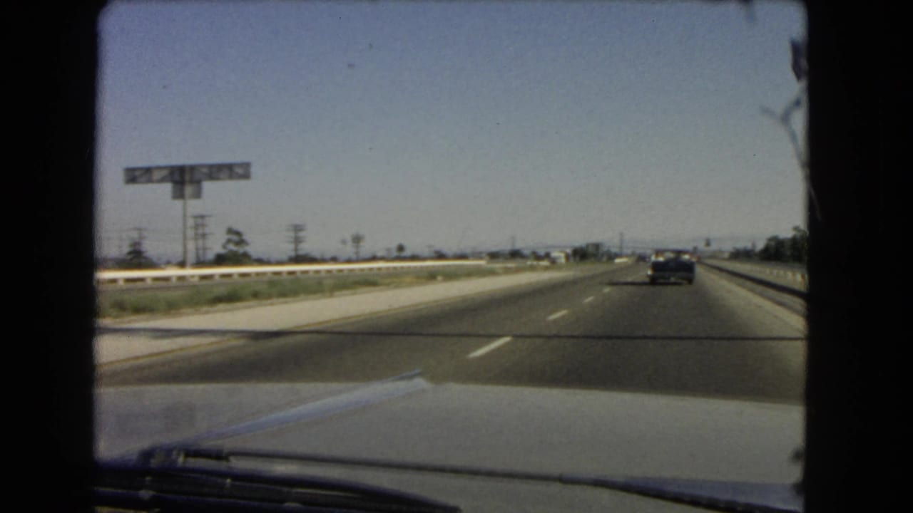 1966 California highway seen from inside a moving car after passing the Anaheim St and Wilmington exit signage.