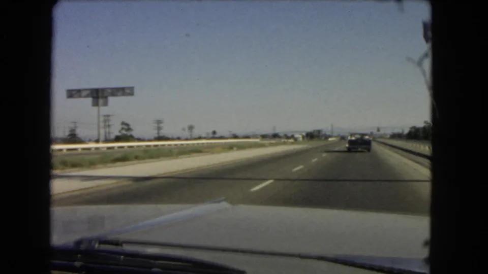 1966 California highway seen from inside a moving car after passing the Anaheim St and Wilmington exit signage.