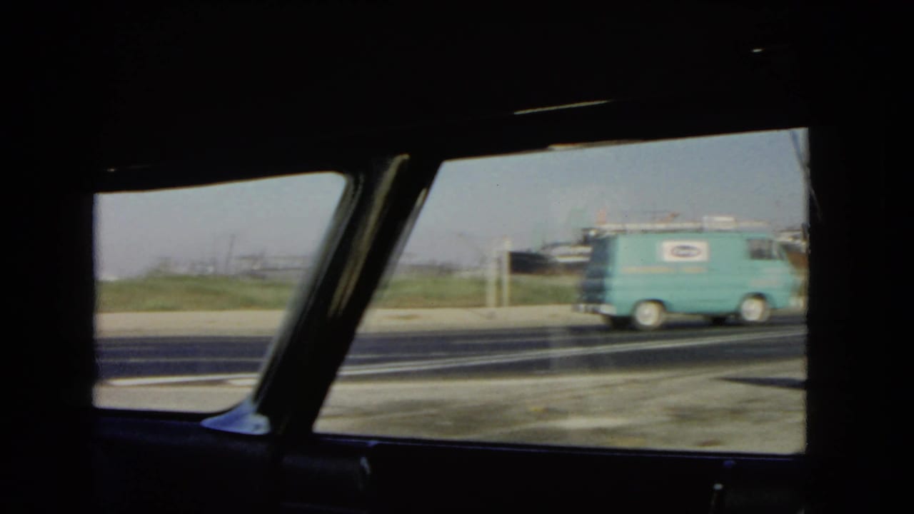 View through a classic car window as a turquoise service van passes on a California highway in 1966.