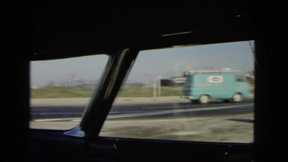 View through a classic car window as a turquoise service van passes on a California highway in 1966.