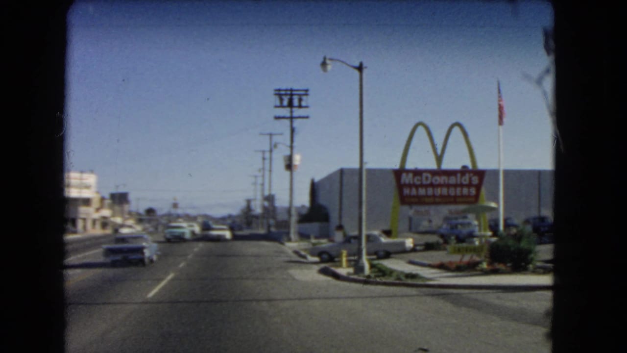 1966 California road view with mid-century cars and a McDonald's golden arches Hamburgers sign beside the street.