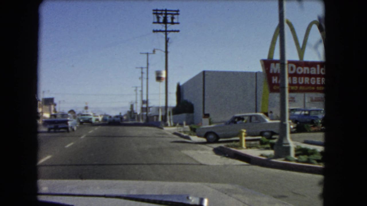 1966 California car-window view of a road beside a vintage McDonald's sign, golden arches, utility poles, and mid-century cars.
