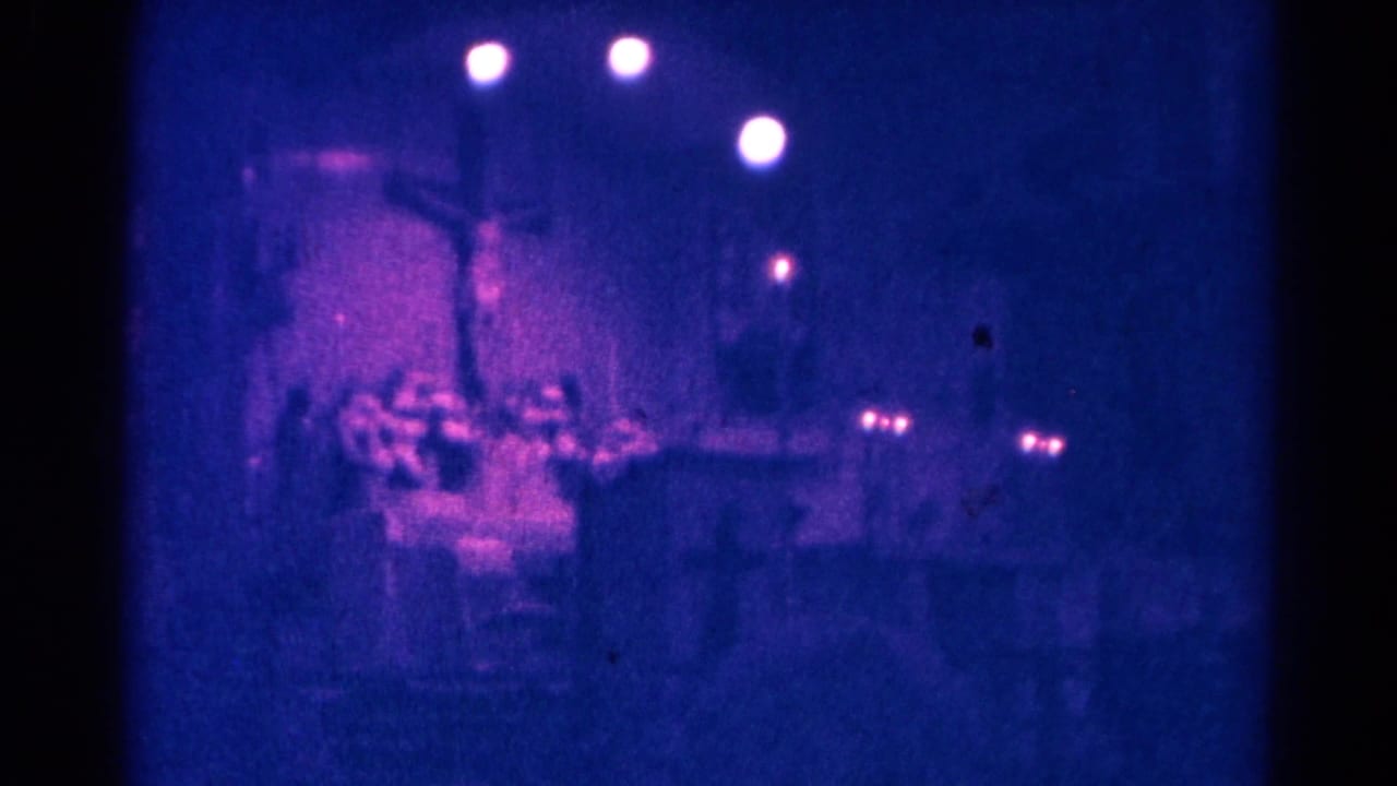 1966 Danville, Illinois 8mm frame showing a dark church sanctuary with a cross, pews, and soft circular lights overhead.