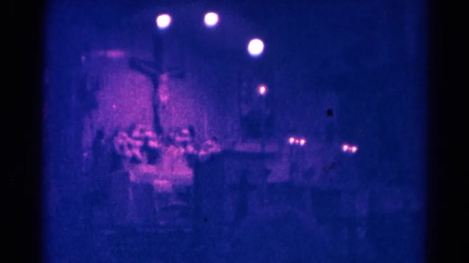 1966 Danville, Illinois 8mm frame showing a dark church sanctuary with a cross, pews, and soft circular lights overhead.