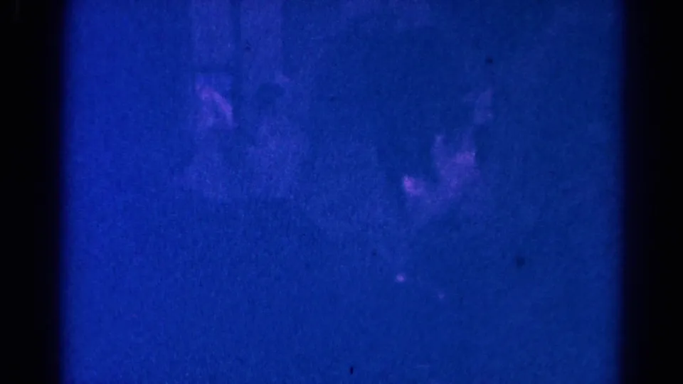 Dim 1966 Danville church ceremony frame showing faint silhouettes of people in formal attire within a blue-shifted interior.