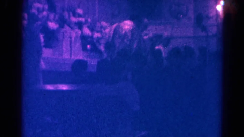 Blue-purple 8mm frame from a 1966 Danville Catholic mass, showing the altar area beyond seated worshippers.